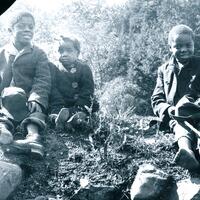 Photograph of three children sitting on a hill
