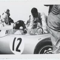 two men talking while one is in a racecar
