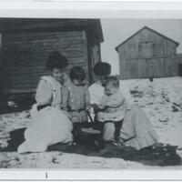 Two mothers and their young children, sitting outside