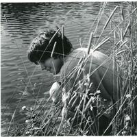 a boy near a lake with plants