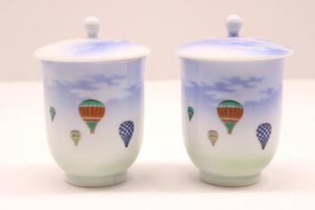 two porcelain containers decorated with paintings of hot air balloons