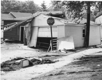 Severely damaged garage on a wreckage-strewn yard.