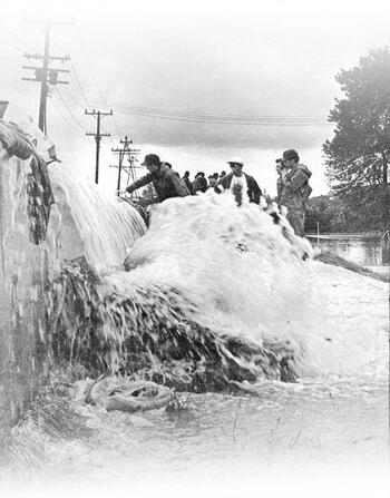 Water comes rushing over the concrete barrier of a dike on Front Street in Olean.